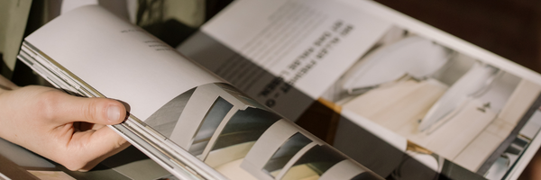 Hands turning the pages of a glossy print magazine spread
