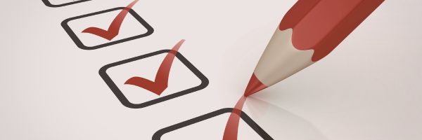 A red pencil checking off boxes on a printed checklist