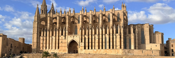 Palma Cathedral in Mallorca, its Gothic spires against a blue sky with scattered clouds