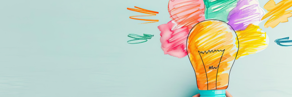 A hand holding up a lightbulb drawing bursting with bright watercolor splashes